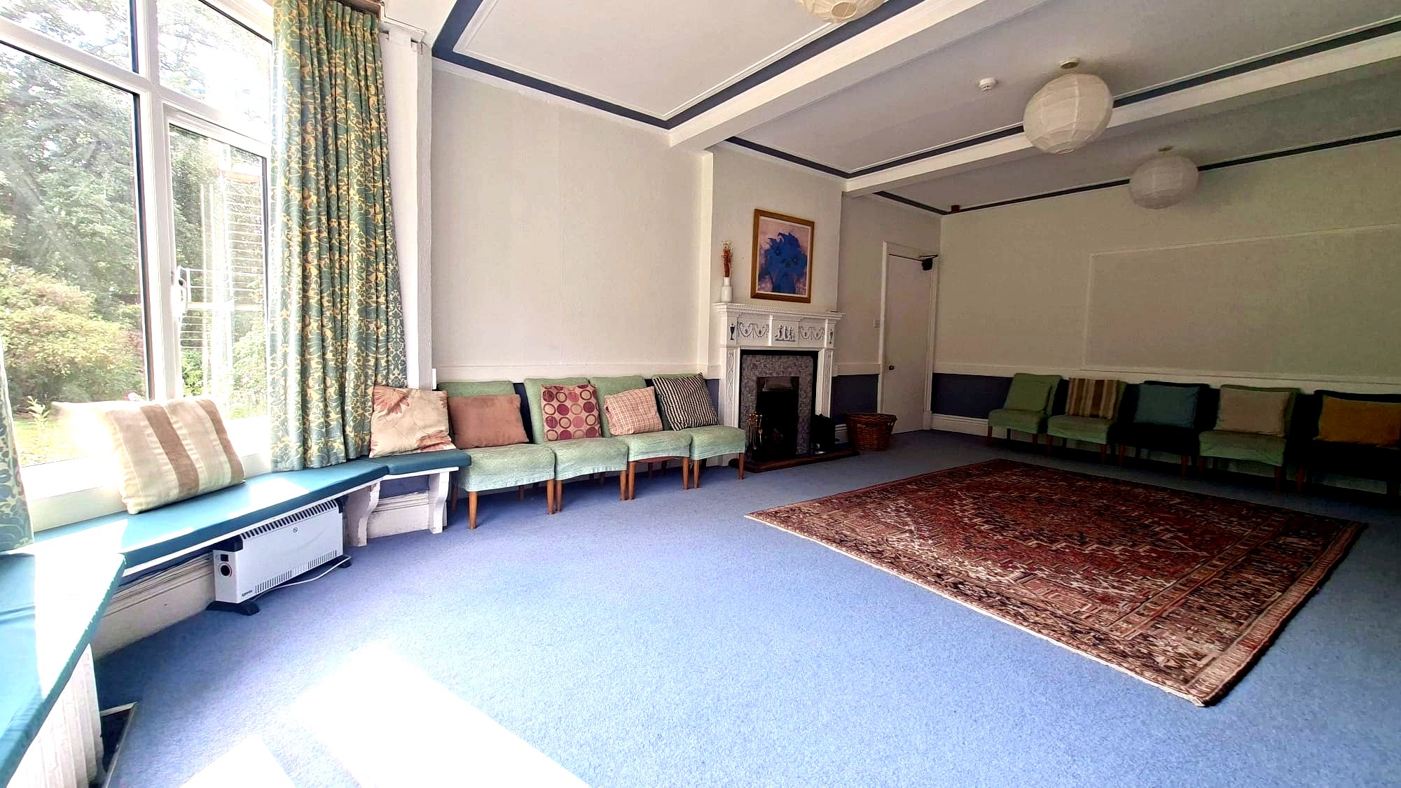 Large meeting room with fireplace, chairs arranged around a Persian rug