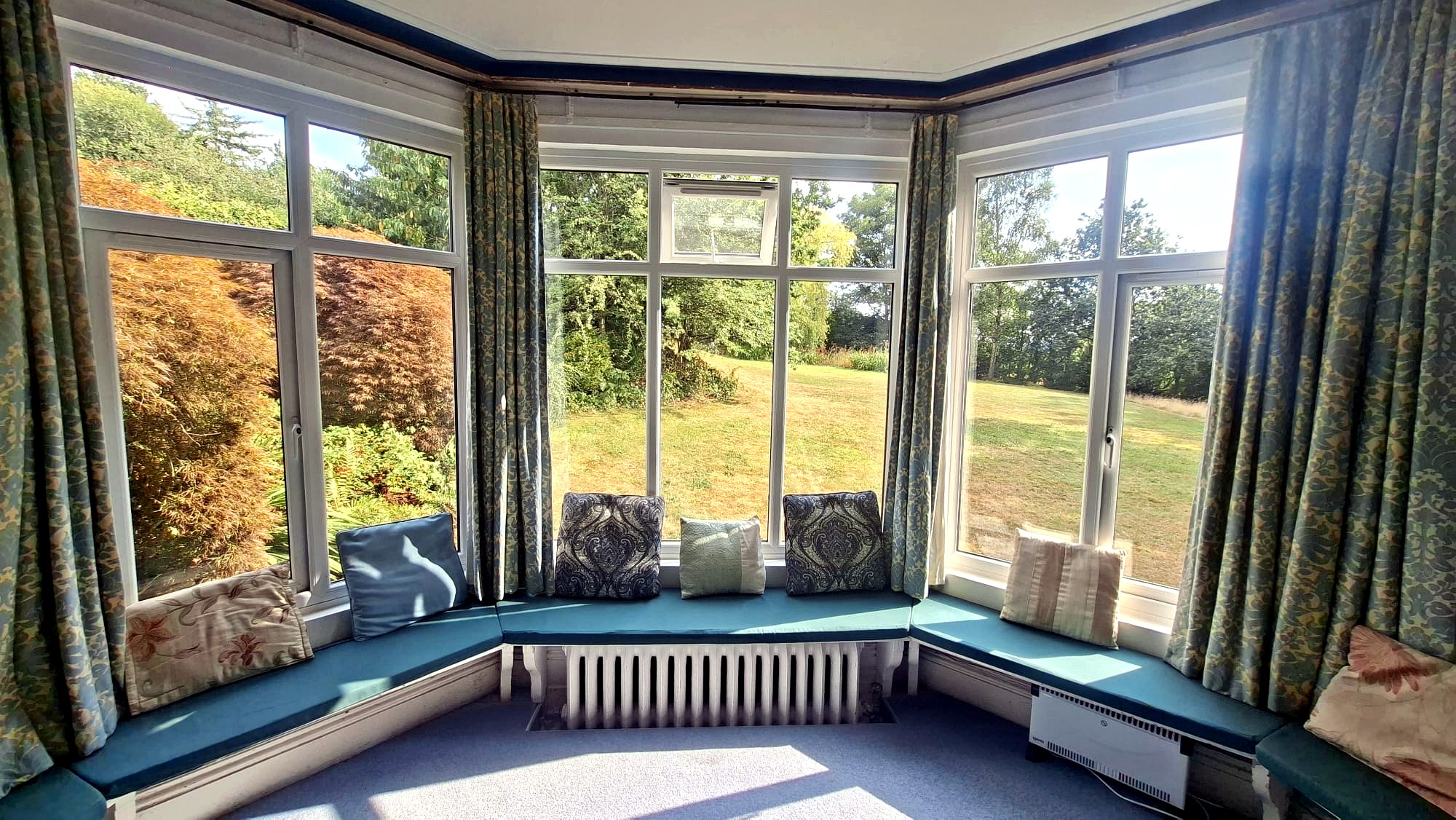 Sunlit bay window seat with garden and trees beyond